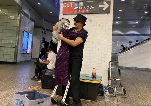 A photo of a subway performer dancing with a skeleton